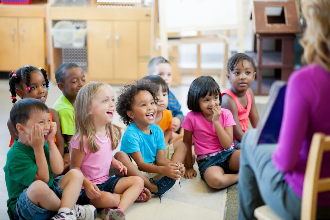 Preschoolers sitting in a circle, listening to their teacher
